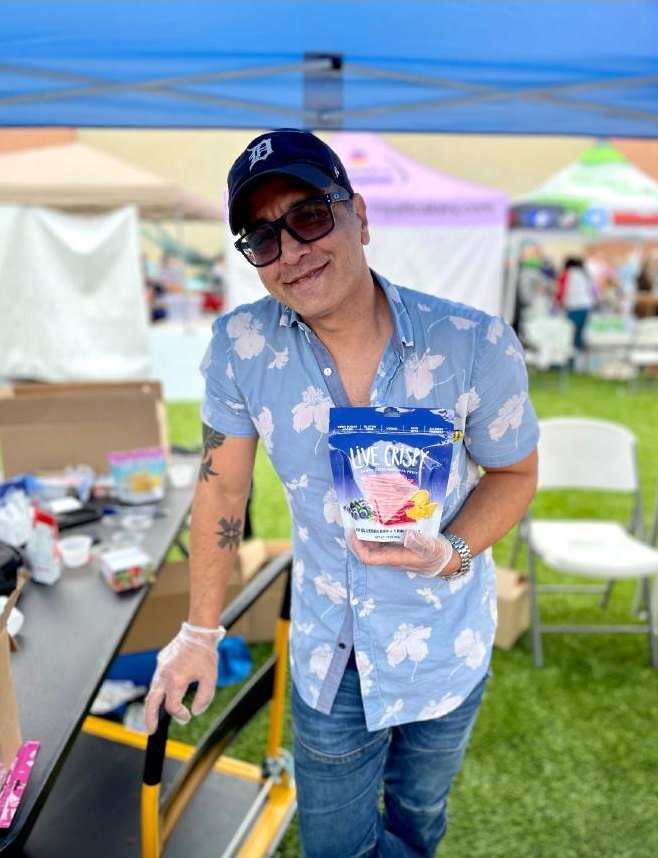Chef Dave holding a bag of Live Crispy at an outdoor market booth