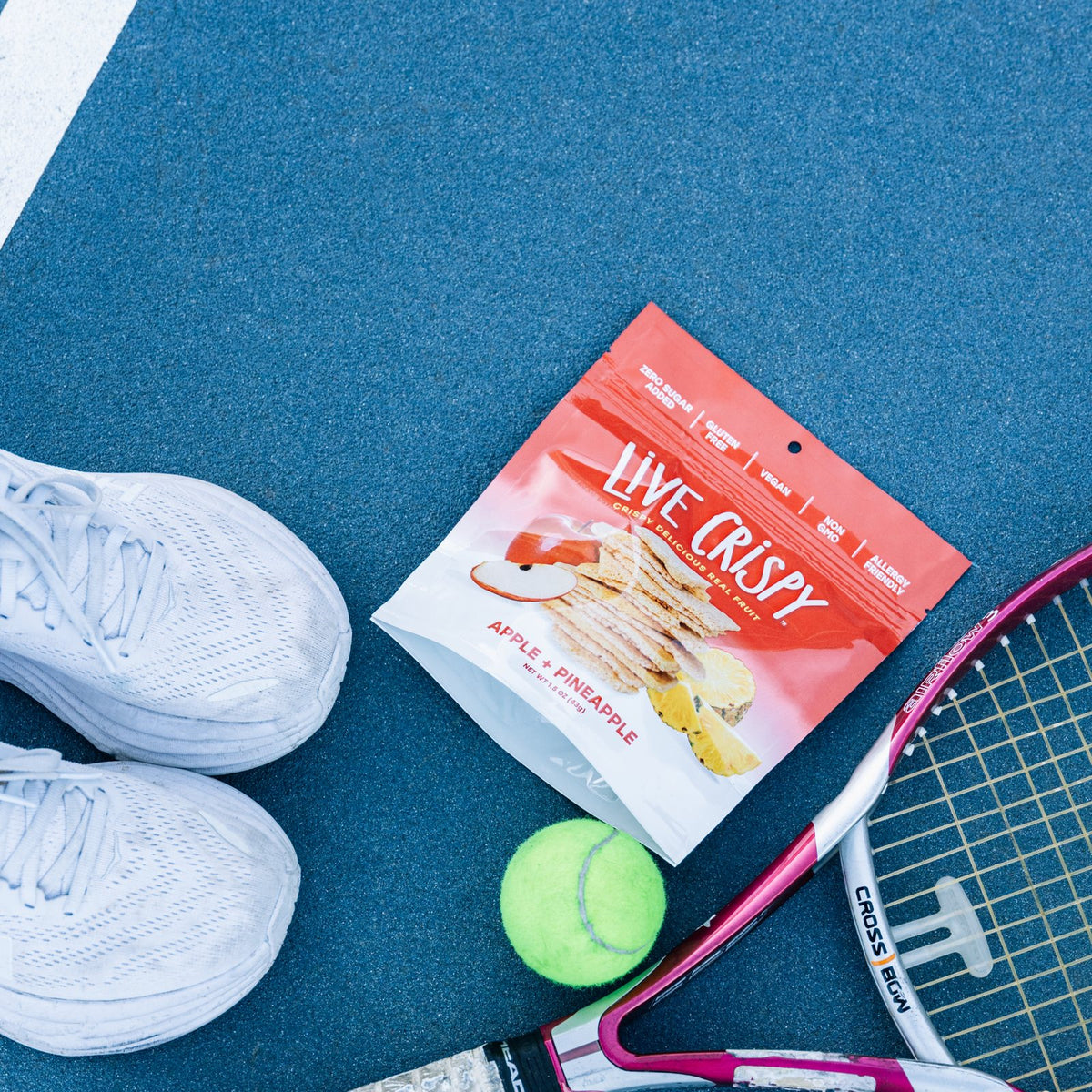 Apple and Pineapple bag on a tennis court with a racket and shoes